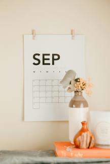 a desk with a calendar and a vase of flowers by Maddi Bazzocco courtesy of Unsplash.