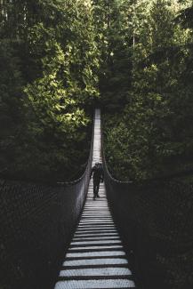 photo of man walking of foot bridge by Liam Simpson courtesy of Unsplash.