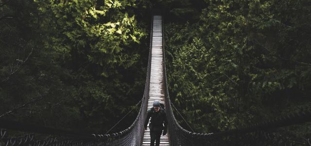 photo of man walking of foot bridge by Liam Simpson courtesy of Unsplash.